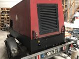 a red and black generator on a trailer in a garage