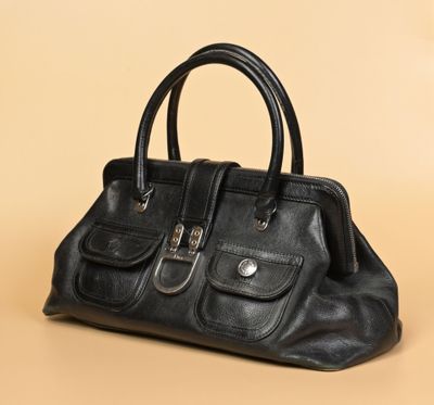 un sac à main noir posé sur une surface beige