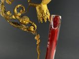 an antique red and gold vase with a bird on top of it