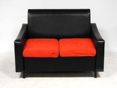 an image of a black leather couch with orange cushions on a white background