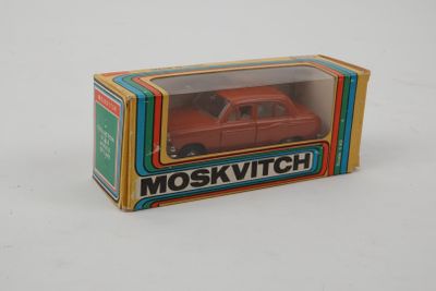 une petite voiture rouge dans une boîte sur une surface blanche