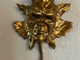 a gold leaf on the wall with a face on it