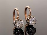 pair of gold and diamond earrings on a reflective surface