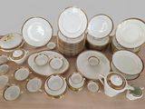 beaucoup d'assiettes et de tasses blanches et dorées sur une table