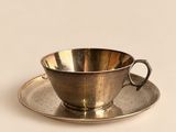 une tasse et une soucoupe en argent posées sur une soucoupe
