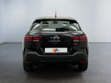 the rear of a black car is parked in a white room