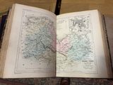 un livre ouvert, sur lequel figure une carte, posé sur une table