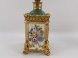 a small gold and green vase with flowers on it