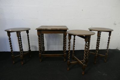 trois tables en bois aux pieds tournés, posées sur un tapis noir