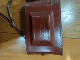 a brown purse with a brown strap on a wooden floor