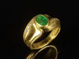 a close up of a gold ring with a green stone