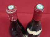two bottles of wine sitting next to each other on a red surface