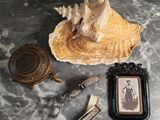 une photo d'une photo représentant une femme assise sur un coquillage, avec un décapsuleur et un porte-clés