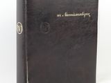 un vieux livre noir orné de lettres dorées, posé sur une surface blanche