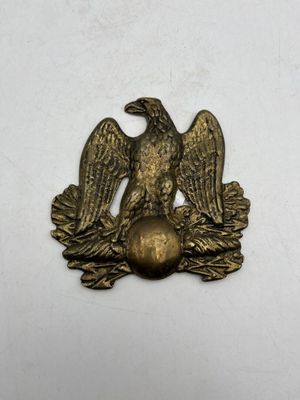 an old brass eagle emblem on a white background