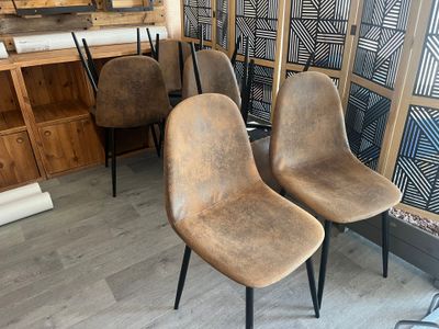 Plusieurs chaises sont alignées dans une pièce, avec un mur derrière elles.