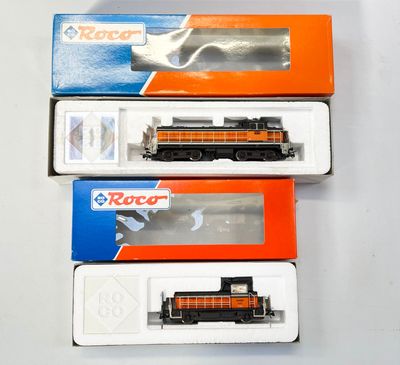trois trains miniatures dans leurs boîtes, empilés les uns sur les autres sur une table