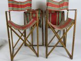 trois chaises pliantes dont les assises sont rayées de rouge et de vert sur fond blanc