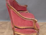 an old chair with a pink upholstered seat on a wooden floor