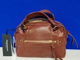 Le sac à main marron est posé sur une table blanche, sur fond bleu.