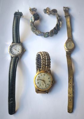 trois montres et un bracelet posés sur une surface blanche