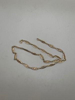 a close up of a gold necklace on a white surface
