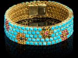 un gros plan sur un bracelet en or orné de pierres bleues et roses