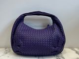 purple woven leather handbag on marble counter top