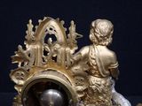 a gold clock with a statue of a boy sitting on top of it