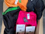 une boîte en carton remplie de vêtements divers, posée par terre