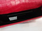 the red purse is sitting on a white surface with a black handle