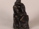 a bronze statue of a man and a woman sitting on a rock