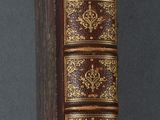an old book sitting on top of a wooden table next to a clock