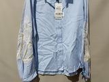 chemise à rayures bleues et blanches avec des manches en dentelle, suspendue à un cintre