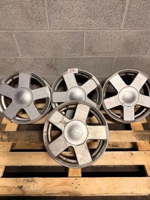 a set of four aluminum wheels on a pallet in a warehouse