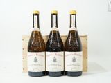 trois bouteilles de vin posées dans une caisse en bois sur une surface blanche