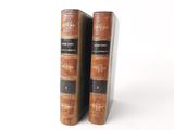 two old books are sitting on a white surface next to each other
