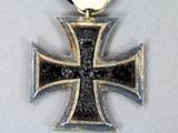 a silver and black cross with a gold medal on it