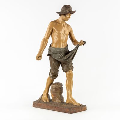 statue en bronze représentant un homme coiffé d'un chapeau et vêtu d'une chemise, assis sur un rocher