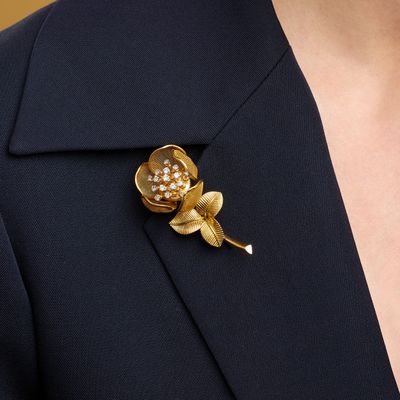 a close up of a person wearing a suit and a flower brooch