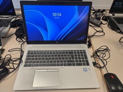 un ordinateur portable posé sur un bureau, à côté d'autres ordinateurs portables