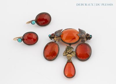 une photo d'une broche et d'une paire de boucles d'oreilles posées sur un fond blanc