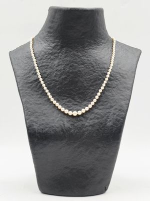 un collier de perles blanches sur un mannequin avec un fermoir en or