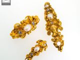 three pieces of gold and pearl jewelry on a white surface