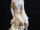 a white statue of a man sitting on top of a rock