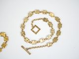 two gold necklaces and a bracelet on a white surface