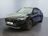 une Audi Q4 noire garée dans une pièce aux murs blancs