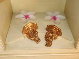 two gold figurines in the corner of a cabinet