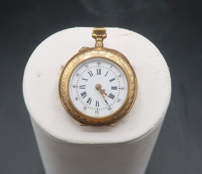 a gold pocket watch sitting on a white pedestal