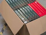 a cardboard box full of dvds sitting on the ground